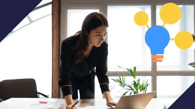 Mulher inclinada sobre uma mesa, concentrada no laptop à sua frente. Ao fundo, há uma janela grande e uma planta. Um ícone de lâmpada com linhas conectadas simbolizando ideias aparece no canto superior direito.